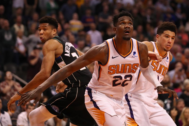   Deandre Ayton #22 and Devin Booker #1 of the Phoenix Suns block out Giannis Antetokounmpo #34 of the Milwaukee Bucks during the second half of the NBA game at Talking Stick Resort Arena on March 04, 2019 in Phoenix, Arizona. The Suns defeated the Bucks 114-105. PHOTO/AFP