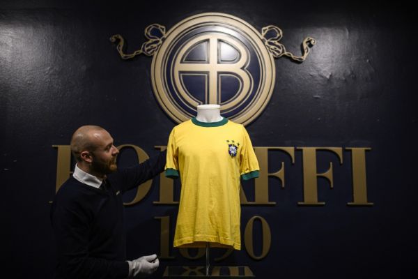 A staff member displays a jersey of Brazilian football legend Pele, during a preview of Sport Memorabilia items, at the Bolaffi auction house in Turin, on November 27, 2019. Online auction of sports memorabilia will be held on December 5, 2019. PHOTO | AFP