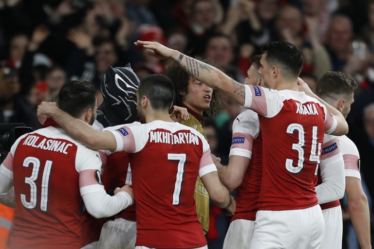 Arsenal's Gabonese striker Pierre-Emerick Aubameyang (2L)wears a mask as he celebrates with teammates after scoring the team's third goal during the UEFA Europa League Round of 16 second leg football match between Arsenal and Rennes at the Emirates Stadium in London on March 14, 2019. 