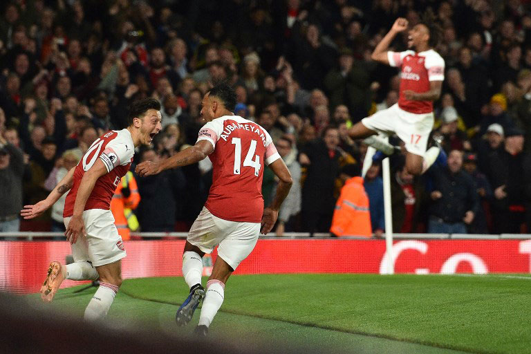Arsenal's Gabonese striker Pierre-Emerick Aubameyang (2nd L) celebrates with Arsenal's German midfielder Mesut Ozil (L) as (Arsenal's Nigerian striker Alex Iwobi reacts behind), after scoring their third goal during the English Premier League football match between Arsenal and Leicester City at the Emirates Stadium in London on October 22, 2018. PHOTO/AFP