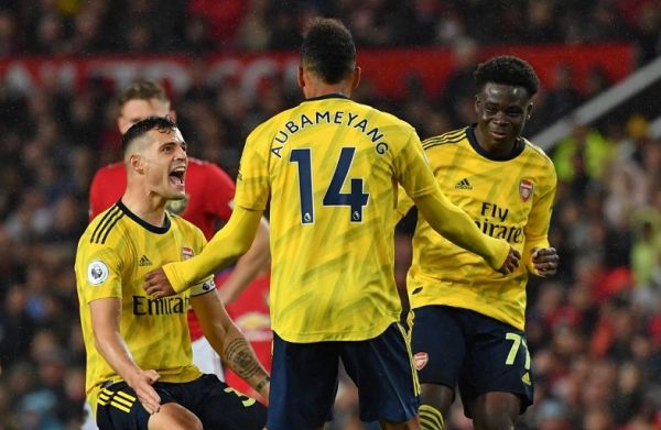 Arsenal's Gabonese striker Pierre-Emerick Aubameyang (C) celebrates with Arsenal's Swiss midfielder Granit Xhaka (L) and Arsenal's English striker Bukayo Saka (R) after scoring their first goal, decision of off-side overturned by VAR (Video Assistant referee) during the English Premier League football match between Manchester United and Arsenal at Old Trafford in Manchester, north west England, on September 30, 2019. PHOTO | AFP