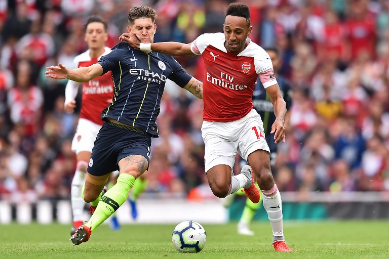 Arsenal's Gabonese striker Pierre-Emerick Aubameyang (R) vies with Manchester City's English defender John Stones during the English Premier League football match between Arsenal and Manchester City at the Emirates Stadium in London on August 12, 2018. Manchester City won the game 2-0. PHOTO/AFP
