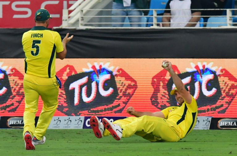 Australian cricketer Mitchell Marsh (R) celebrates with teammate Aaron Finch (L) after taking a catch to dismiss unseen Pakistan batsman Hasan Ali during the second T20 cricket match between Pakistan and Australia at The International Cricket Stadium in Dubai on October 26, 2018. PHOTO/AFP