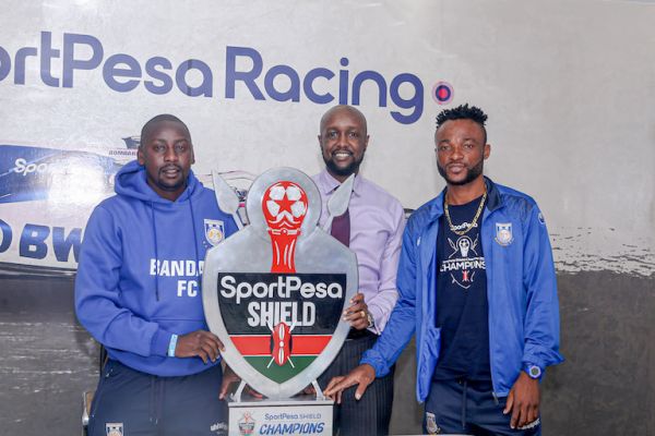 Bandari FC head coach, Bernard Mwalala (left) and his captain Felly Mulumba (right) pose with the SportPesa CEO Captain Ronald Karauri when they presented him with the 2019 SportPesa Shield trophy. PHOTO/SPN/Anthony Mwaki