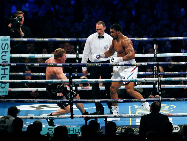 Britain's Anthony Joshua (R) knocks Russia's Alexander Povetkin to the canvas in the 7th round during their boxing world Heavyweight title fight at Wembley Stadium in north west London on September 22, 2018. Britain's Anthony Joshua retained his International Boxing Federation, World Boxing Association and World Boxing Organisation heavyweight titles with a seventh-round stoppage of Alexander Povetkin at London's Wembley Stadium on September 22, 2018. PHOTO/AFP