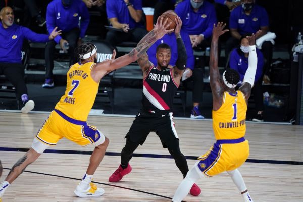 Damian Lillard #0 of the Portland Trail Blazers tries to pass under pressure from JaVale McGee #7 and Kentavious Caldwell-Pope #1 of the Los Angeles Lakers during the second half in Game 1 of Round 1 of the NBA Playoffs at AdventHealth Arena at ESPN Wide World Of Sports Complex on August 18, 2020 in Lake Buena Vista, Florida. PHOTO | AFP