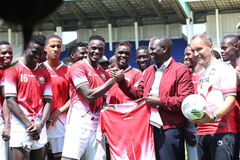 Deputy President, William Ruto (red jacket),  being presented with the team jersey by captain Victor Wanyama when he visited Harambee Stars players at Moi International Sports Centre,Kasarani in Nairobi on Friday, October 12, 2018.PHOTO/SPORTPICHA
