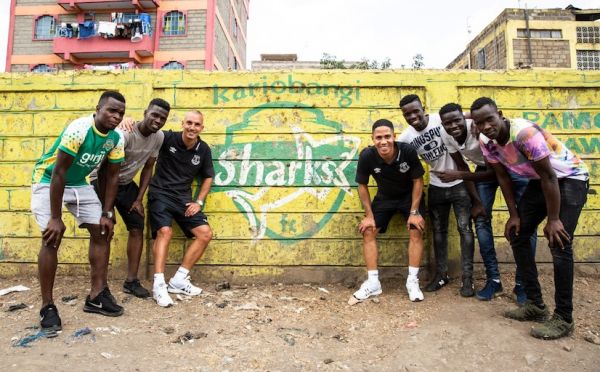 Everton FC ambassadors, Steven Pienaar (4th right) and Leon Osman (third left) pose at a Kariobangi Sharks FC mural with local youth when they visited the Nairobi estate where the Blues opponents hail from in Nairobi on Friday, July 5, 2019. PHOTO/SPN 