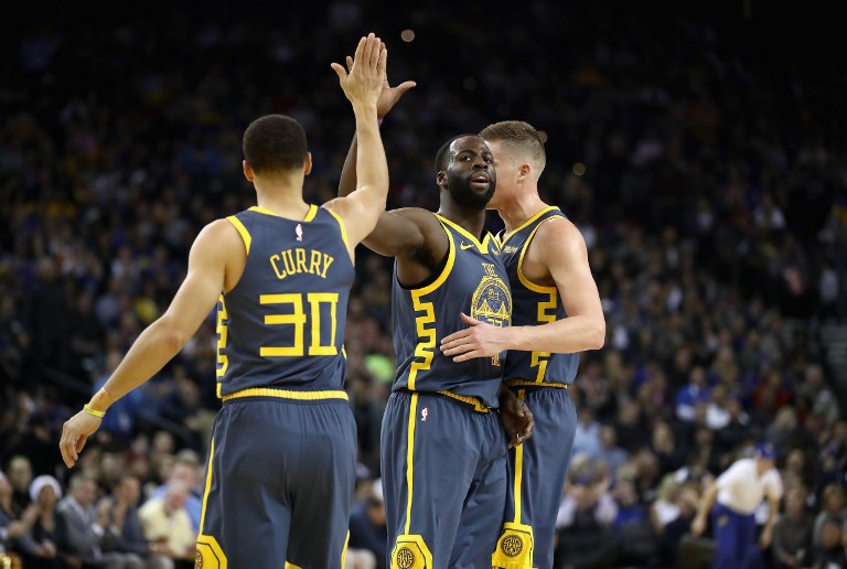 Jonas Jerebko #21, Draymond Green #23, and Stephen Curry #30 of the Golden State Warriors congratulate one another after the Warriors made a basket against the Toronto Raptors at ORACLE Arena on December 12, 2018 in Oakland, California. PHOTO/AFP