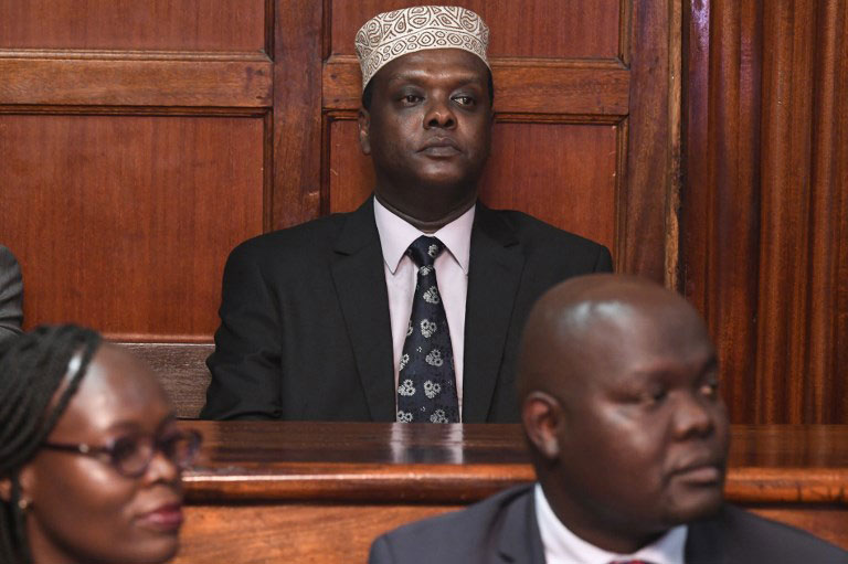 Kenya's Ambassador to Austria and former Sports minister Hassan Wario (C) sits the dock at the Mililani Court on October 19, 2018 after he was charged with corruption in the Rio Olympics and abuse of office. Wario has been charged along with five former government and national Olympic committee officials over the misappropriation of more than 55 million shillings ($545,000). PHOTO/AFP
