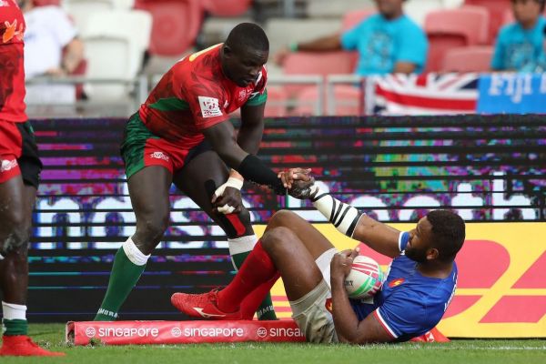 Kenya's Bush Mwale helps France's Tavite Veredamu to get up from the floor on day two of the HSBC World Rugby Sevens Series in Singapore on 14 April, 2019. PHOTO/Mike Lee/KLC fotos for World Rugby