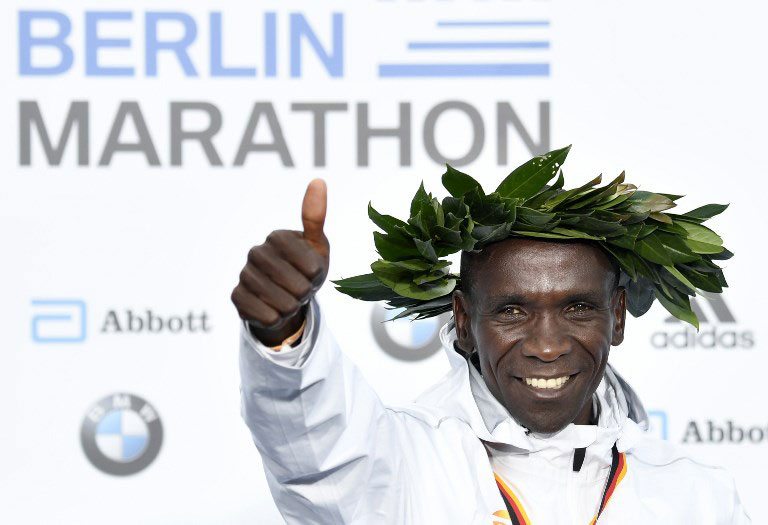Kenya's Eliud Kipchoge celebrates on the podium during the winner's ceremony after winning the Berlin Marathon setting a new world record on September 16, 2018 in Berlin. PHOTO/AFP