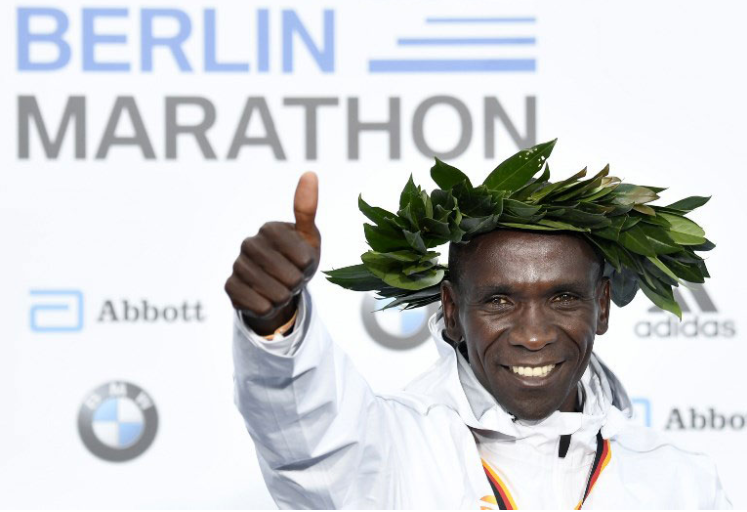 Kenya's Eliud Kipchoge celebrates on the podium during the winner's ceremony after winning the Berlin Marathon setting a new world record on September 16, 2018 in Berlin. PHOTO/AFP