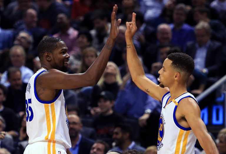 Kevin Durant #35 and Steph Curry #30 of the Golden State Warriors high five during the first half of an NBA game against the Toronto Raptors at Air Canada Centre on November 16, 2016 in Toronto, Canada. PHOTO/AFP