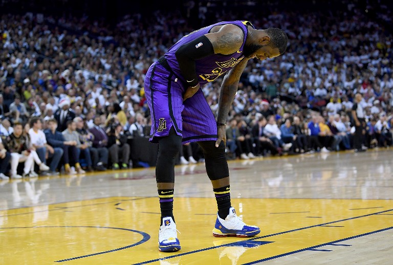 LeBron James #23 of the Los Angeles Lakers leans over in pain after he was hurt against the Golden State Warriors during the second half of their NBA Basketball game at ORACLE Arena on December 25, 2018 in Oakland, California. LeBron James left with a groin injury but the Los Angeles Lakers regrouped for a 127-101 blowout win over two-time defending champion Golden State that snapped an 11-game losing streak on the Warriors' home court.