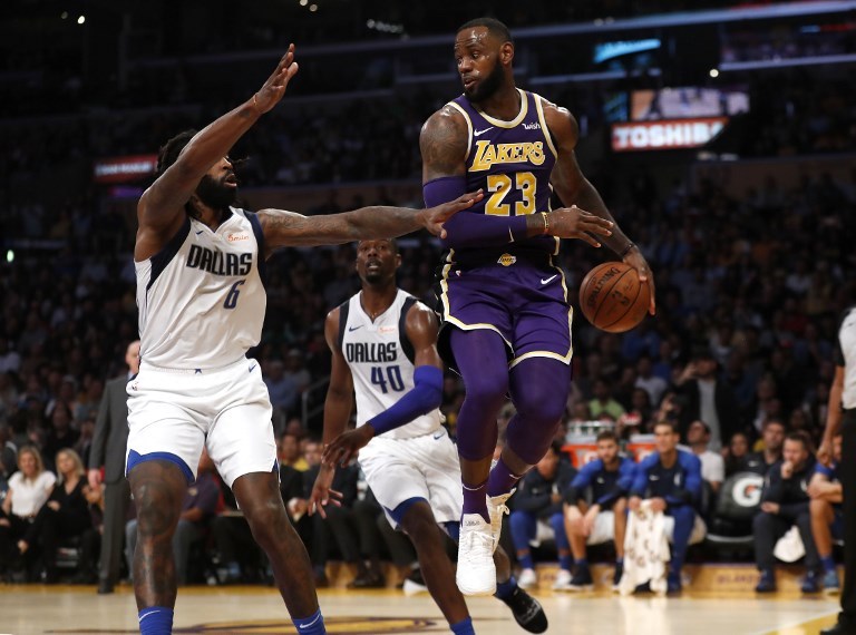 LeBron James (right) of the Los Angeles Lakers passes the ball past DeAndre Jordan (6) and Harrison Barnes (40) of the Dallas Mavericks during the second half of a game at Staples Center on October 31, 2018 in Los Angeles, California. PHOTO/AFP