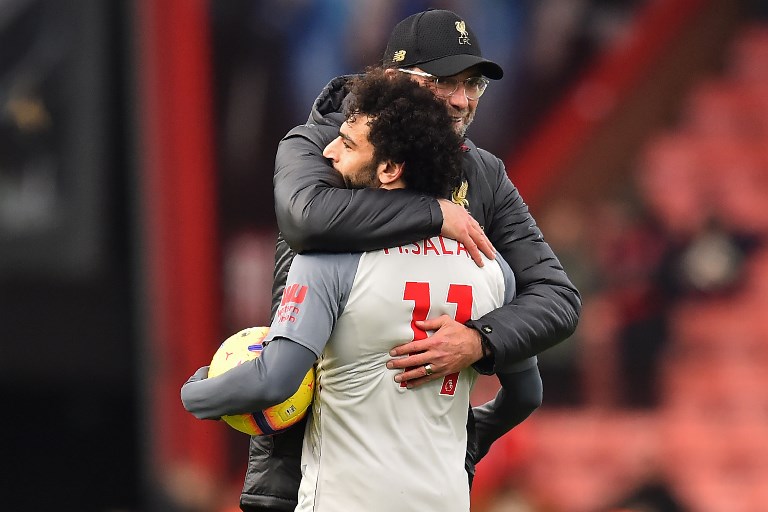 Liverpool's Egyptian midfielder Mohamed Salah (L) holding the match-ball for scoring a hat-trick is embraced by Liverpool's German manager Jurgen Klopp (R) on the pitch after the English Premier League football match between Bournemouth and Liverpool at the Vitality Stadium in Bournemouth, southern England on December 8, 2018. Liverpool won the game 4-0. PHOTO/AFP
