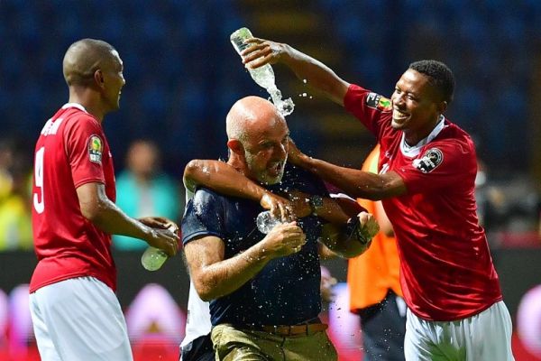 Madagascar's forward Faneva Andriatsima (L) and Madagascar's forward Tsilavina Njiva (R) pour water on Madagascar's coach Nicolas Dupuis (C) as they celebrate winning the 2019 Africa Cup of Nations (CAN) Group B football match between Madagascar and Nigeria at the Alexandria Stadium on June 30, 2019. PHOTO | AFP