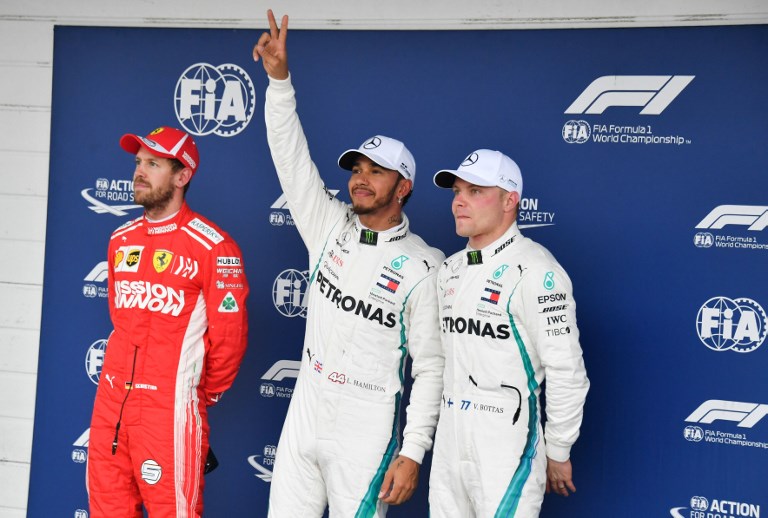 Mercedes' British driver Lewis Hamilton (C) celebrates after taking the pole position, next to Ferrari's German driver Sebastian Vettel (L) who took the second place and Mercedes' Finnish driver Valtteri Bottas (R) who took the third place, after the qualifying session for the F1 Brazil Grand Prix at the Interlagos racetrack in Sao Paulo, Brazil on November 10, 2018.PHOTO/ AFP