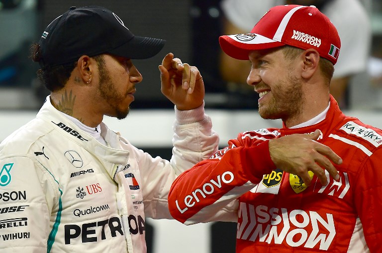 Mercedes' British driver Lewis Hamilton (L) slap hands with Ferrari's German driver Sebastian Vettel (R, third place) after taking the pole position in the qualifying session at the Yas Marina circuit on November 24, 2018, in Abu Dhabi, ahead of the Abu Dhabi Formula One Grand Prix. PHOTO/AFP