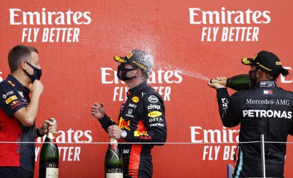 Mercedes' British driver Lewis Hamilton (R) sprays champagne at race winner Red Bull's Dutch driver Max Verstappen (C) on the podium after the F1 70th Anniversary Grand Prix at Silverstone on August 9, 2020 in Northampton. The race commemorates the 70th anniversary of the inaugural world championship race, held at Silverstone in 1950. PHOTO | AFP