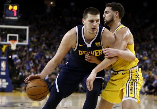 Nikola Jokic (15) of the Denver Nuggets is guarded by Klay Thompson (11) of the Golden State Warriors at ORACLE Arena on April 02, 2019 in Oakland, California. PHOTO/AFP