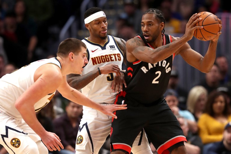 Nikola Jokic #15 and Torrey Craig #3 of the Denver Nuggets guard Kawhi Leonard #2 the Toronto Raptors at the Pepsi Center on December 16, 2018 in Denver, Colorado. PHOTO/AFP