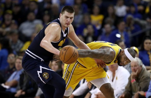 Nikola Jokic #15 of the Denver Nuggets and DeMarcus Cousins #0 of the Golden State Warriors go for a loose ball at ORACLE Arena on April 02, 2019 in Oakland, California. PHOTO/AFP