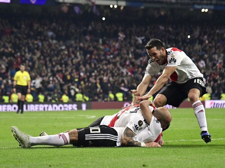 River Plate's Gonzalo Martinez (on the ground) celebrates with teammates Javier Pinola (C) and Uruguayan Camilo Mayada after scoring against Boca Juniors during the second leg match of the all-Argentine Copa Libertadores final, at the Santiago Bernabeu stadium in Madrid, on December 9, 2018. PHOTO/AFP