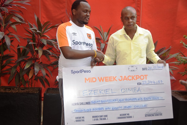 SportPesa Midweek Jackpot winner, Ezekiel Oimba (left) receives his cheque from SportPesa News Content Editor, Louis Kalinga in Mombasa on December 24, 2018. PHOTO/SPN
