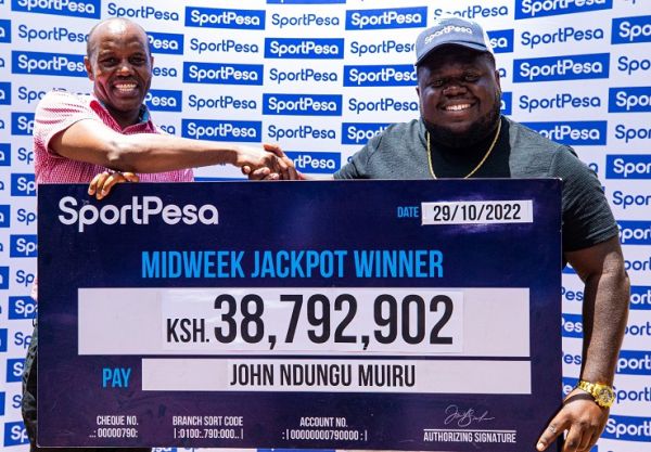 SportPesa Midweek Jackpot winner John Ndung'u Muiru poses with his winners cheque after winning KSHs 38,792,902. PHOTO | SPN