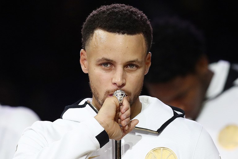 Stephen Curry #30 of the Golden State Warriors kisses at his 2017-2018 Championship ring prior to their game against the Oklahoma City Thunder at ORACLE Arena on October 16, 2018 in Oakland, California. PHOTO/AFP