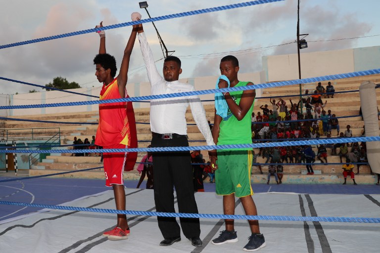 The referee raises the hand of the winner during a match in a ring installed at the Wish Stadium in Mogadishu on November 15, 2018. Somalia has held its first boxing competition in over three decades, with young boxers in the conflict-torn nation dreaming of a career on the international stage. The three-day light-weight boxing competition, which wrapped up on November 18, took place in the capital Mogadishu where the athletes faced off in a ring set up on a basketball court, surrounded by ruined buildings bearing the scars of the country's long conflict.PHOTO/AFP