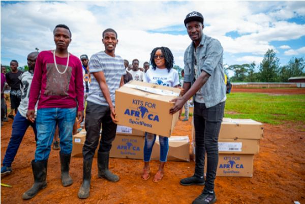 Tusker FC's Humphrey Mieno (left) together with SportPesa's Digital Communications Executive Triza Akoth hand a box of kits to one of the teams at the Umeme Grounds in Ziwani on Wednesday, November 27, 2019. PHOTO | Duncan Sirma | SPN