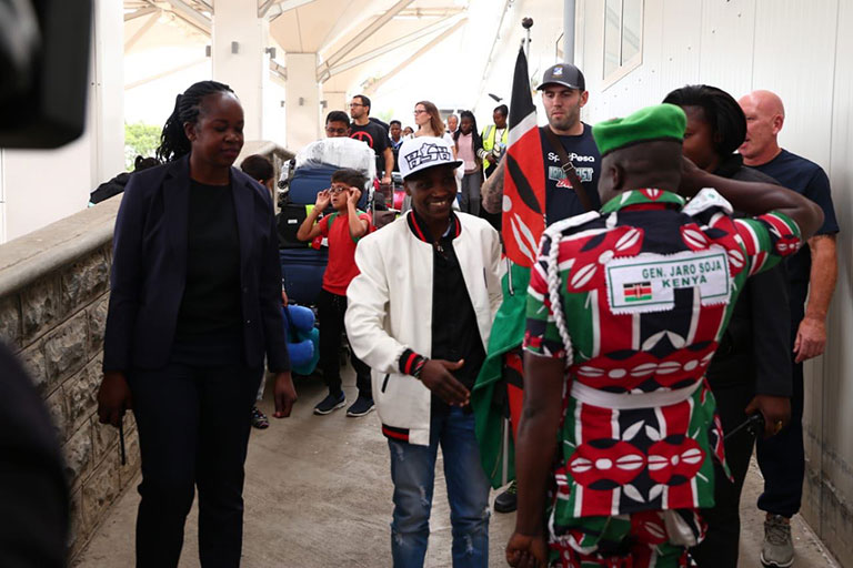WELCOME FIT FOR A QUEEN: WBC Super Bantamweight champion, Fatuma Zarika (centre) is saluted by the self-styled Chief of K'Ogalo Defence Forces, Jared 'Jaro Soja' Otieno upon her arrival at JKIA from the UK on Saturday, September 1, 2018. PHOTO/SPN