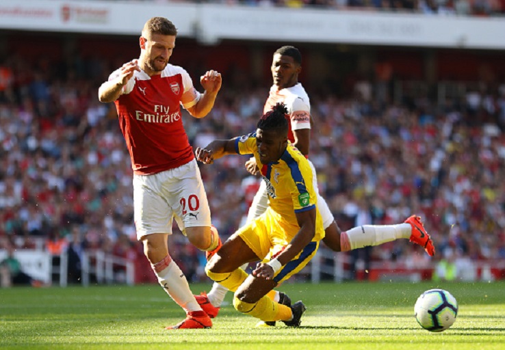 Wilfried Zaha of Crystal Palace is challenged by Shkodran Mustafi of Arsenal during the Premier League match between Arsenal FC and Crystal Palace at Emirates Stadium on April 21, 2019 in London, United Kingdom.PHOTO/GETTY IMAGES