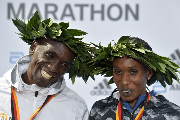 Winner Kenya's Eliud Kipchoge (L) and women's winner Kenya's Gladys Cherono pose after the winner's ceremony after the Berlin Marathon on September 16, 2018 in Berlin. PHOTO/AFP
